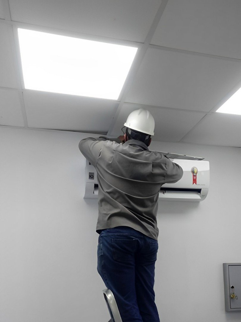 Foto da página sobre - Funcionário do Grupo Silvestre dando manutenção em ar condicionado